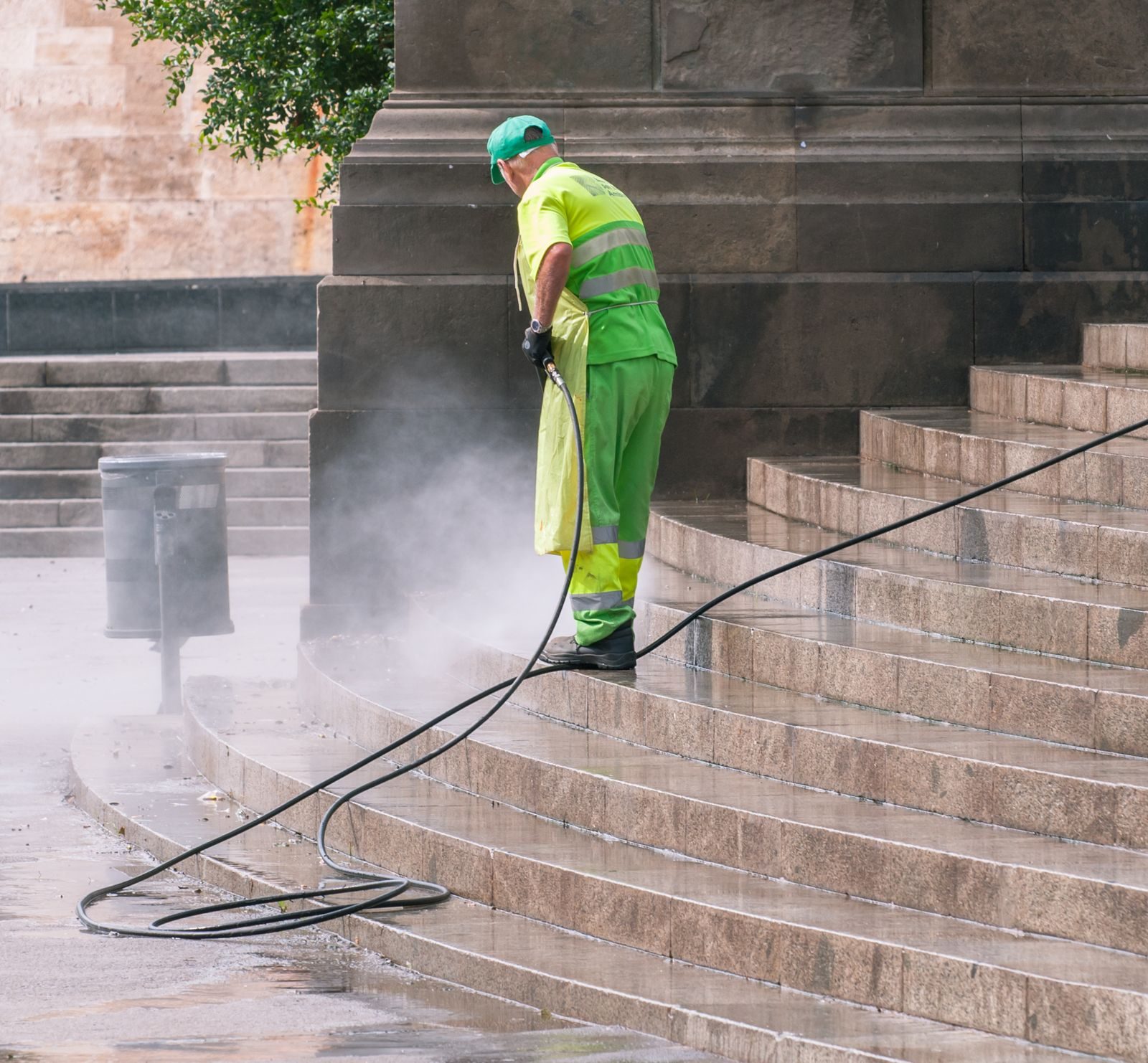 Worker power washing stone steps with a pressure washer